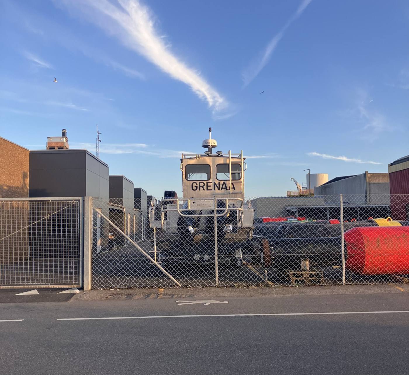Arbejdsbåd med navnet Grenaa på havnen bag et hegn