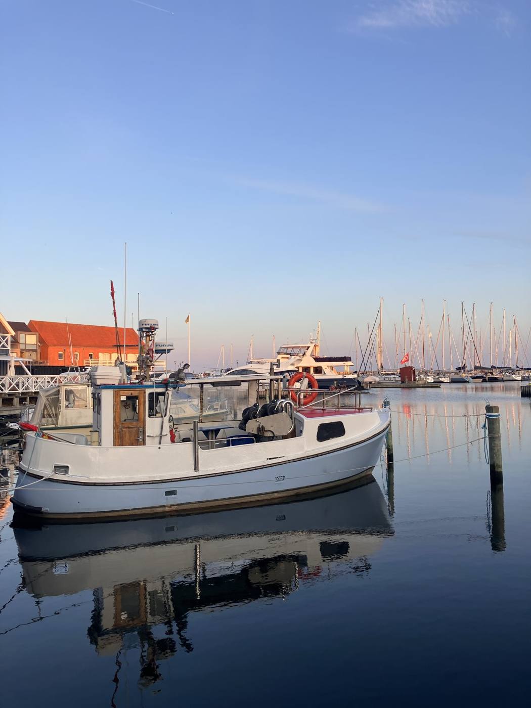 Hvid båd ved broen i Grenaa Marina med sejlbåde i baggrunden